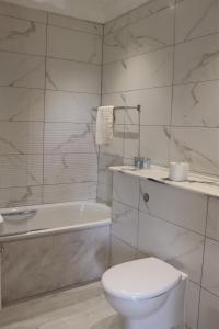 a white bathroom with a toilet and a bath tub at Portclew House in Pembroke