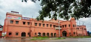 een groot rood bakstenen gebouw met een bord erop bij Heritage B.R Hotel Suites and Restaurant in Chittagong