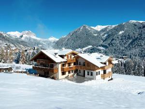 a house in the snow with mountains in the background at Casa Davarda in Vigo di Fassa