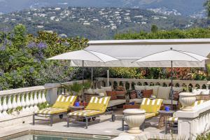 a patio with chairs and an umbrella and a pool at Bastide les 3 Portes in Saint-Paul-de-Vence