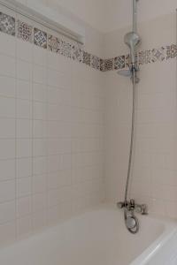 a shower in a white tiled bathroom with a tub at Eiffel Tower Saint Residence in Paris