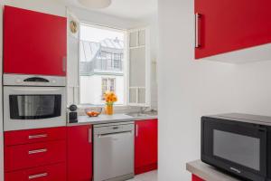 a kitchen with red cabinets and a microwave at Eiffel Tower Saint Residence in Paris