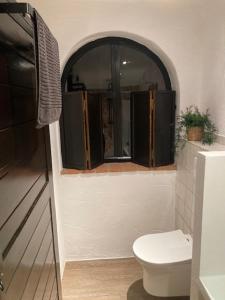 baño con aseo y ventana en Casa del Sueño, en Álora