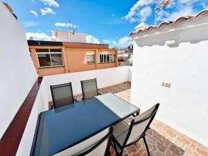 Un balcón con una mesa y sillas en un tejado. en Coqueto ático de playa, en Fuengirola