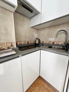 Una cocina con gabinetes blancos y un fregadero. en Coqueto ático de playa, en Fuengirola 15 fotos más