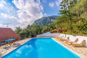 a swimming pool with lounge chairs and a mountain at Villa Yiannakis in Nisakion