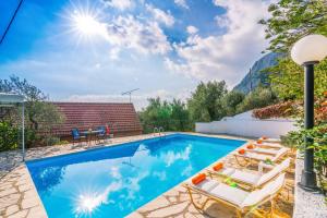 a swimming pool with chairs and a house at Villa Yiannakis in Nisakion