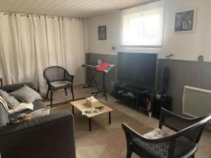 a living room with a couch and a tv at Villa au coeur de la vallée in Thyez