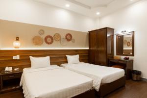 een hotelkamer met 2 bedden en een spiegel bij Lantern Hotel in Ho Chi Minh-stad