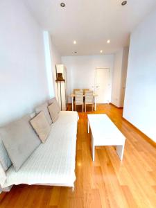 salon z białą kanapą i stołem w obiekcie Maravilla Apartment w Sewilli