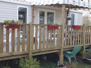 a wooden deck with potted plants and a chair at Mobile home 6 personnes in Sainte-Reine-de-Bretagne +2 photos