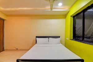 a bed in a room with a yellow wall at OYO HOTEL NANDAN in Bhubaneshwar