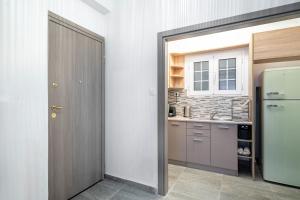 a kitchen with a door leading into a kitchen with a refrigerator at Modern Pagrati - Greecing in Athens