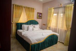 Schlafzimmer mit einem großen Bett mit einem grünen Kopfteil in der Unterkunft Enny'scourt Service Apartment in Akure