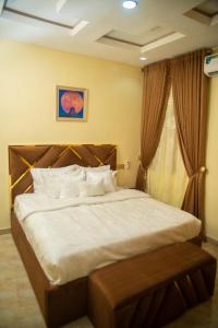 a bedroom with a large bed with white sheets and a window at Enny'scourt Service Apartment in Akure