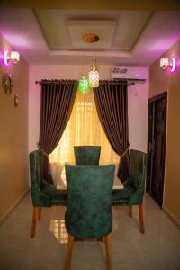 a dining room table with green chairs and a window at Enny'scourt Service Apartment in Akure