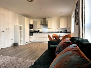 a living room with a couch and a kitchen at Luxury Modern 2 Bed Apartment in Ebbsfleet - 20mins from London in Swanscombe