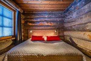 Dormitorio con cabaña de madera y cama con almohadas rojas en Villa Poronperä, en Kuusamo