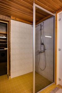 een douche in een badkamer met gele tegels bij Villa Poronperä in Kuusamo