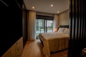 a bedroom with a bed and a large window at Loft 406 Parque Una + garagem in Pelotas