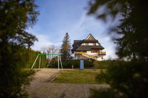 a house on a hill with a playground in front of it at Koślówka in Biały Dunajec