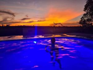 Casa em sítio à beira do Rio Piracicaba c/ piscina في ساو بيدرو: شخص يسبح في مسبح ذو اضاءة زرقاء