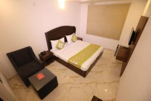 a small bedroom with a bed and a chair at Hotel Kelvish Plaza-Near IGI Airport Terminal-3 in New Delhi