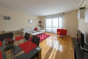 ein Wohnzimmer mit einem weißen Sofa und roten Stühlen in der Unterkunft Cituspace Las Tablas Azofra in Madrid