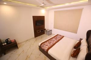 a bedroom with a bed and a flat screen tv at Hotel Kelvish Plaza-Near IGI Airport Terminal-3 in New Delhi