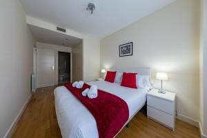 ein Schlafzimmer mit einem großen weißen Bett mit roten Kissen in der Unterkunft Cituspace Las Tablas Azofra in Madrid