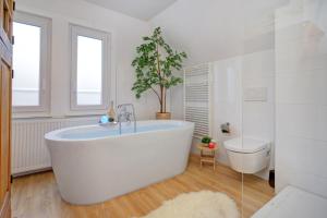 a large white bathroom with a tub and a toilet at Familienglück im Schwarzwaldhaus mit Schlossblick in Neuenbürg