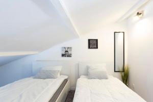 2 camas en una habitación con paredes blancas en Chez Stéphane - Superbe T3 climatisé à proximité de la plage avec parking, en Le Grau-du-Roi