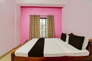 a bedroom with a large bed with a pink wall at OYO Mahalaxmi lodge in Cuttack