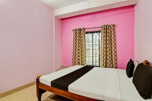 a bedroom with a bed and a pink wall at OYO Mahalaxmi lodge in Cuttack