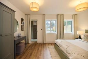 a bedroom with a bed and a desk and windows at The Wembley Park Secret - Spacious 3BDR Flat with Terrace in London