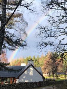 a rainbow in the sky over a house at Drumguish Cottage in Kingussie