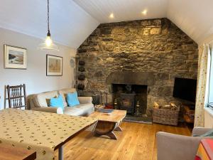 a living room with a stone wall with a fireplace at Drumguish Cottage in Kingussie