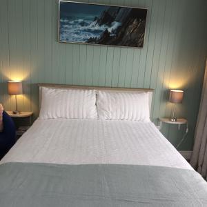 a bedroom with a white bed with two lamps at Kates Place Studio 1 in Donegal
