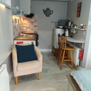 a living room with a chair and a kitchen at Kates Place Studio 1 in Donegal