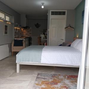 a bedroom with a white bed and a kitchen at Kates Place Studio 1 in Donegal