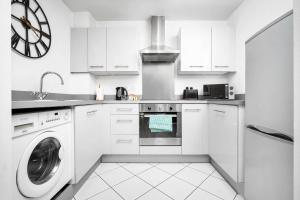 a white kitchen with a washing machine and a clock at Luxury Birmingham City Centre Apartment - Balcony - Free Wifi & Netflix - Top Rated -126S in Birmingham