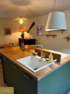 um balcão de cozinha com um lavatório e uma luz em L'éco-Domaine du Chalonge em Héric