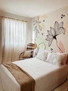 1 dormitorio con 1 cama con una flor en la pared en Apê na principal rota do litoral sul - Reserve103 en Ipojuca