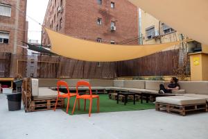 a woman sitting on a couch on a patio with chairs at Onefam Les Corts in Barcelona