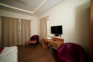 um quarto de hotel com uma cama, uma secretária e uma televisão em Doves Danta Resort, Coorg em Cherambane