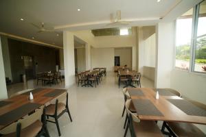 um restaurante com mesas e cadeiras de madeira e janelas em Doves Danta Resort, Coorg em Cherambane