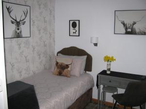um quarto com uma cama com uma secretária e cabeças de veado na parede em Fairfield Townhouse Guest House Selfcatering em Inverness