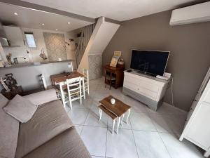 a living room with a couch and a tv and a table at Appartement 2 Chambres avec Climatisation et Jardin, à 400m de la Plage - Les Issambres - FR-1-768-72 in La Garonnette-Plage +3 photos