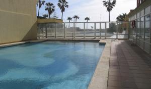 a swimming pool outside of a building with palm trees at Carihuela in Torremolinos