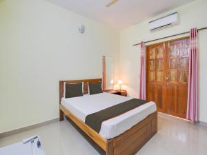 1 dormitorio con 1 cama y puerta de madera en Collection O Shadowline Guesthouse en Goa